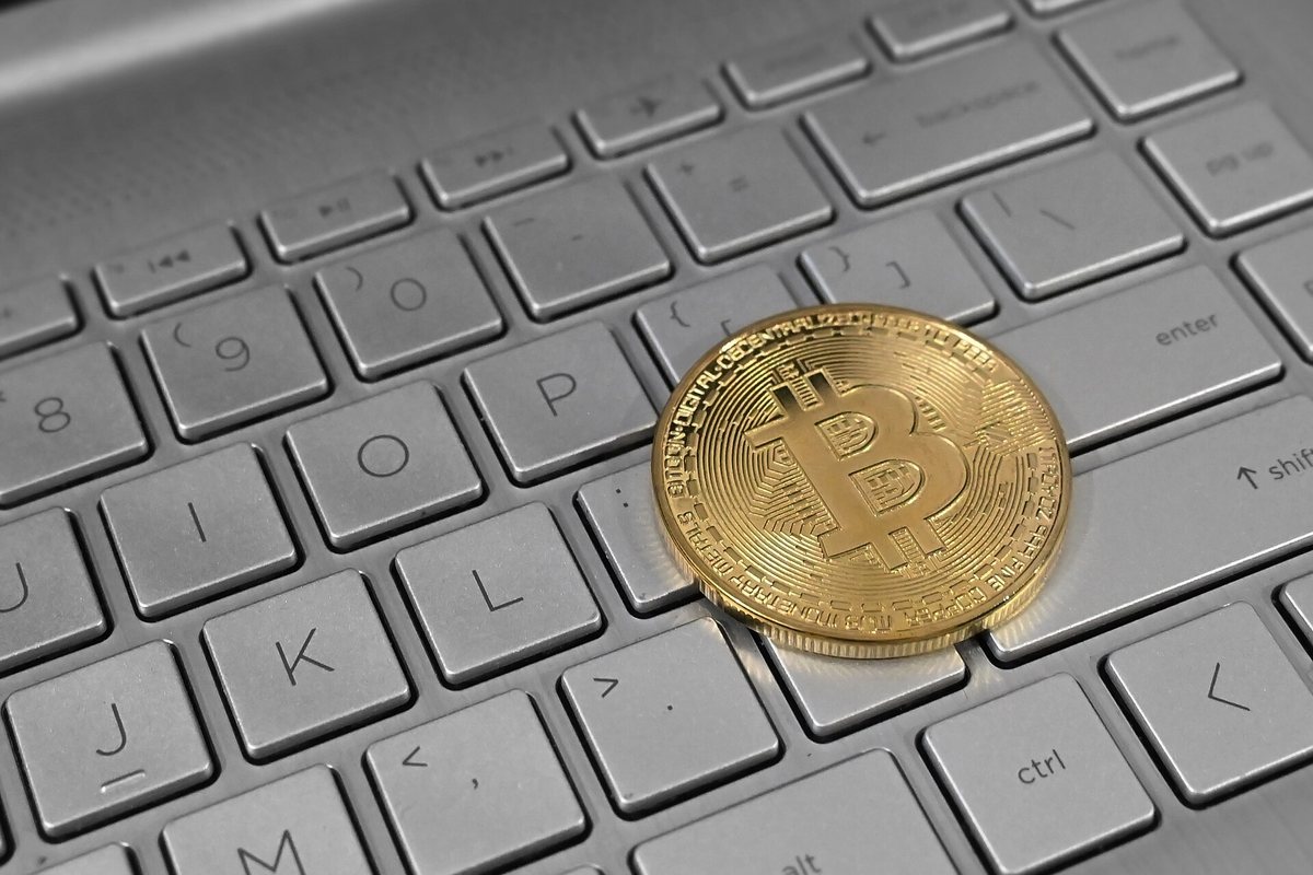 Gold Bitcoin coin resting on a laptop keyboard