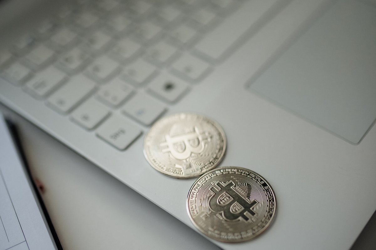 Two silver Bitcoin coins resting on a laptop keyboard